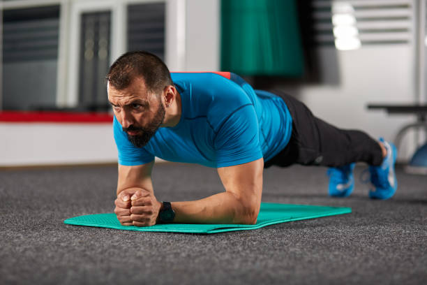 istock Fitness trainer doing planks in the gym 891329550