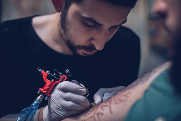 istock Artist making tattoo on customer's hand in studio 891330790