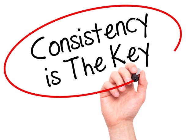 Man Hand writing Consistency is The Key with black marker on visual screen