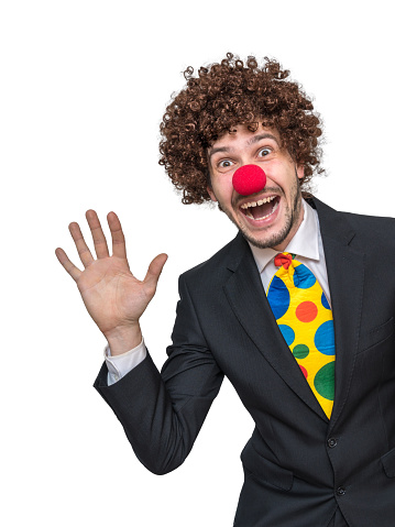Happy businessman in suit and clown costume is waving with hand. Isolated on white background.