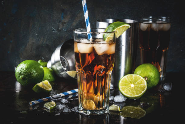 Cuba Libre, long island cocktail Cuba Libre, long island or iced tea cocktail with strong alcohol, cola, lime and ice, two glass, dark background copy space cuba libre stock pictures, royalty-free photos & images