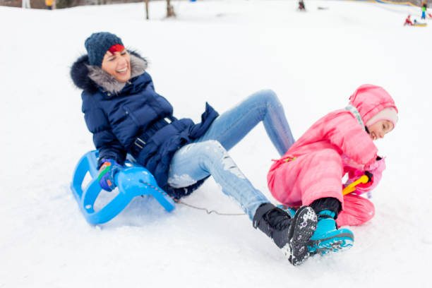istock Mother and Daughter Falling from the Sled on a ski-slope 891373664
