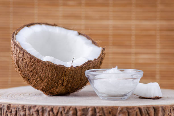 organic coconut oil in a glass bowl and coconut on natural brown background coconut oil in a glass bowl and coconut on natural background exotic pets photos stock pictures, royalty-free photos & images