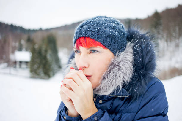 istock Adult woman Blowing into her Hands on a Cold Winter day 891373708