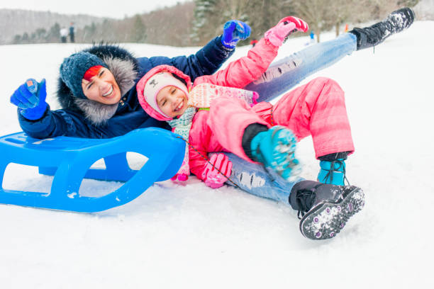 istock Mother and Daughter Falling from the Sled on a ski-slope 891373716