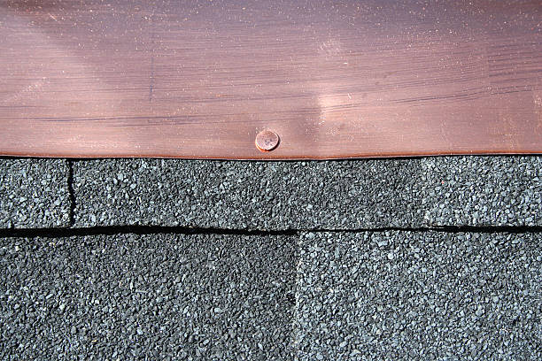 Black asphalt roofing shingles with copper flashing stock photo