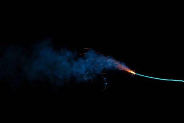 Photo of Burning fuse with sparks and blue smoke isolated on black background