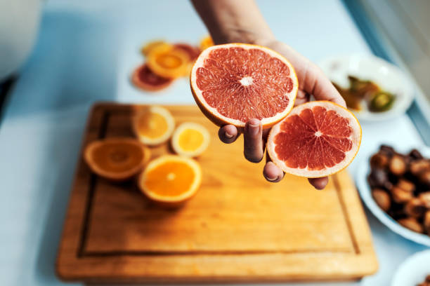 istock Hand holding Cut grapefruits and lemons on wooden cutting board 891381592