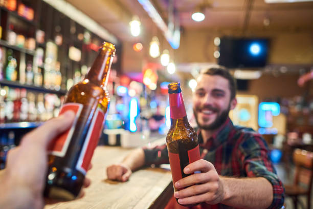 istock Happy Young Man Clinking Bottles with Friend in Bar 891385170