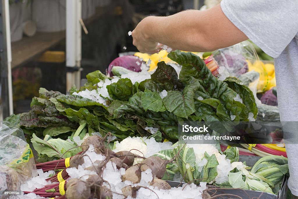 Mercato degli agricoltori di operaio si diffonde ghiaccio su verdure biologiche - Foto stock royalty-free di Abbondanza