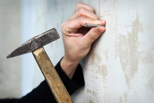 istock Close up on a hand hammering a nail on a wall 891404540
