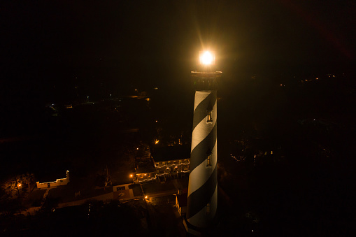 Aerial image of a bright lit lighthouse at night