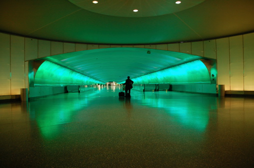 Lone Woman Traveler leaning on her suitcase watching the Light Show in the Detroit Airport Underground Pedestrian Tunnel.