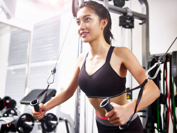 young asian woman exercising in gym using equipment