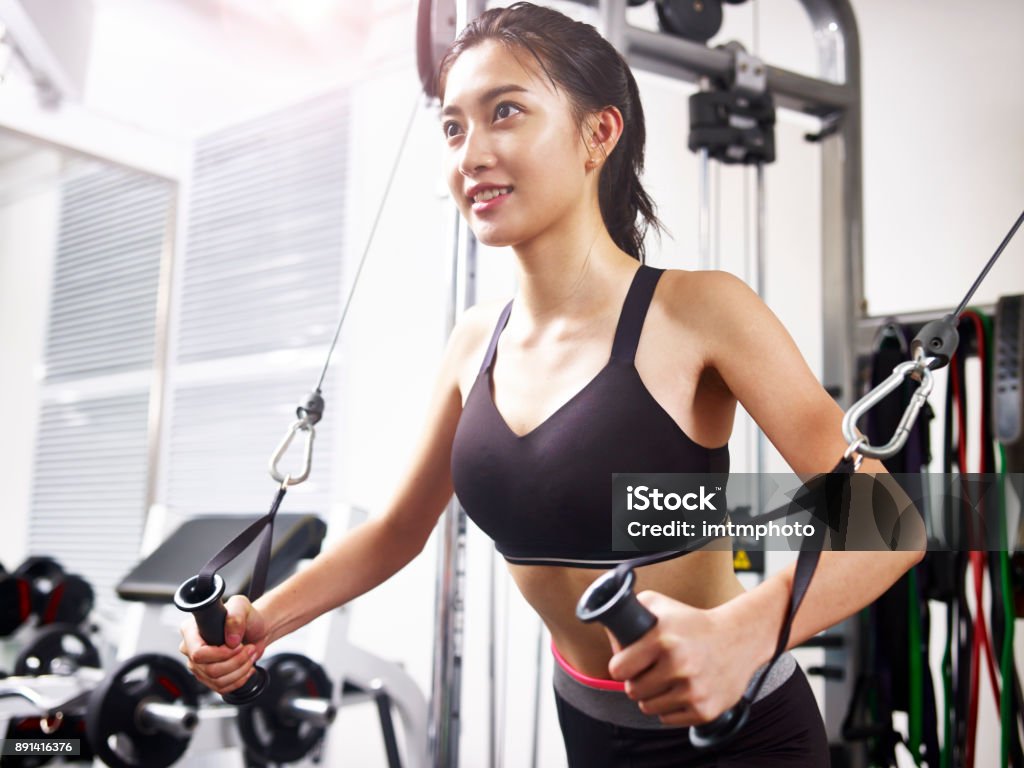 young asian woman exercising in gym using equipment happy young asian woman working out in gym using exercising equipment. Gym Stock Photo