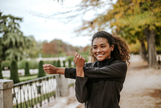 公園でストレッチ運動を行う陽気な若い女性。 - running jogging african descent nature ストックフォトと画像