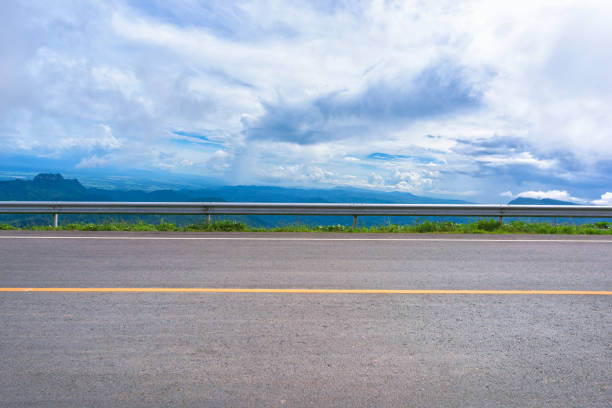 Asphalt road and mountains landscape under morning sky with clouds
