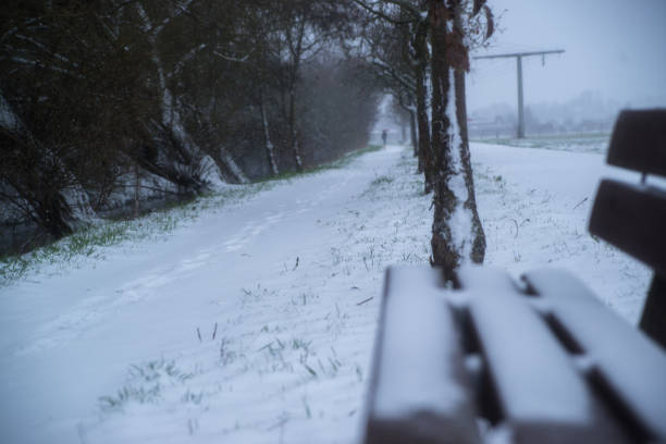 snow covered wooden sitting bench in park at winter