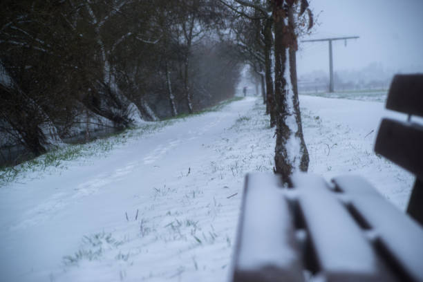 snow covered wooden sitting bench in park at winter