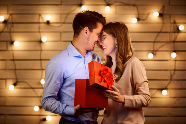 The guy gives a gift box to his girlfriend. stock photo