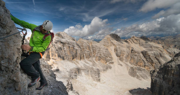 hombre trepador en una escarpada y expuesta vía ferrata - corvara fotografías e imágenes de stock