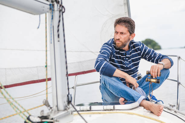 istock man sits on bow of sailing yacht and holds binoculars 891447138