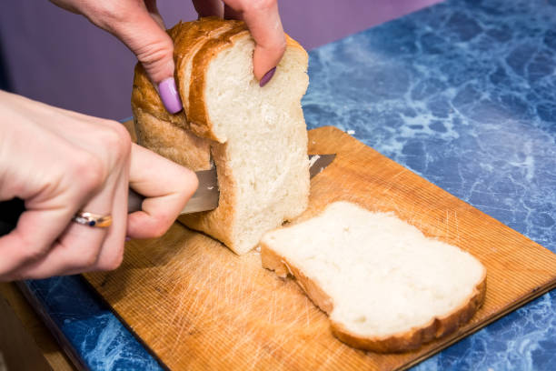istock Female hands cut bread on wooden board 891447824