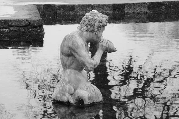 escultura de piedra de un tritón, en el jardín público de hellbrunn. salzburgo, austria. - mythology snow winter austria fotografías e imágenes de stock