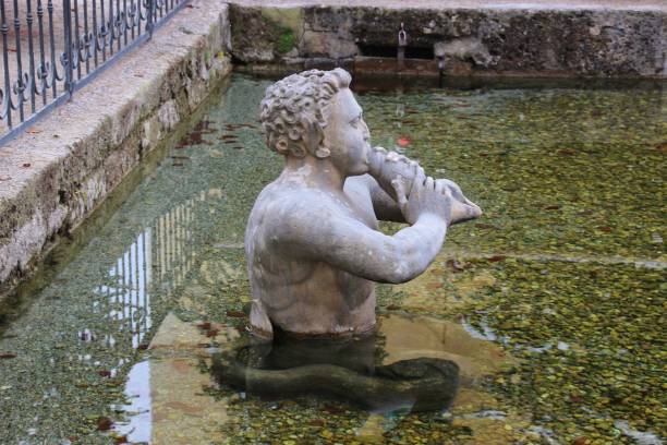 escultura de piedra de un tritón, en el jardín público de hellbrunn. salzburgo, austria. - mythology snow winter austria fotografías e imágenes de stock