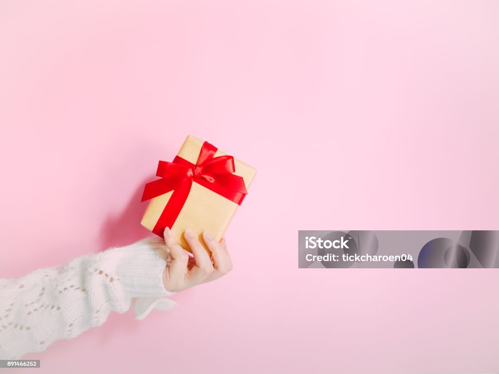 concept for christmas and new year event with beauty hand woman with winter cloth holding gold gift box and give it to pauper person with isolated pink background Adult Stock Photo