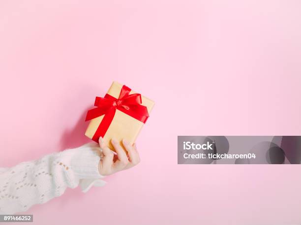 Concept For Christmas And New Year Event With Beauty Hand Woman With Winter Cloth Holding Gold Gift Box And Give It To Pauper Person With Isolated Pink Background Stock Photo - Download Image Now