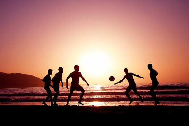 pôr do sol de futebol - beach football imagens e fotografias de stock