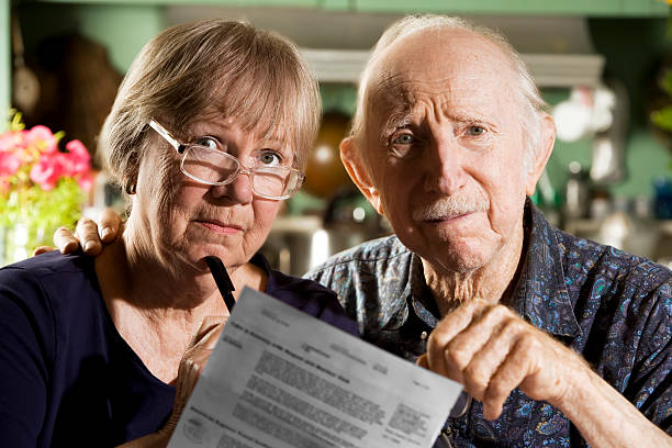 A concerned elderly couple reviewing a document stock photo
