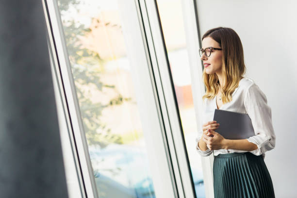 istock Young businesswoman standing next to the window with digital tablet 891482996