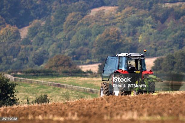 Tractor Ploughing Un Campo Foto de stock y más banco de imágenes de Agricultura - Agricultura, Tractor, Granja