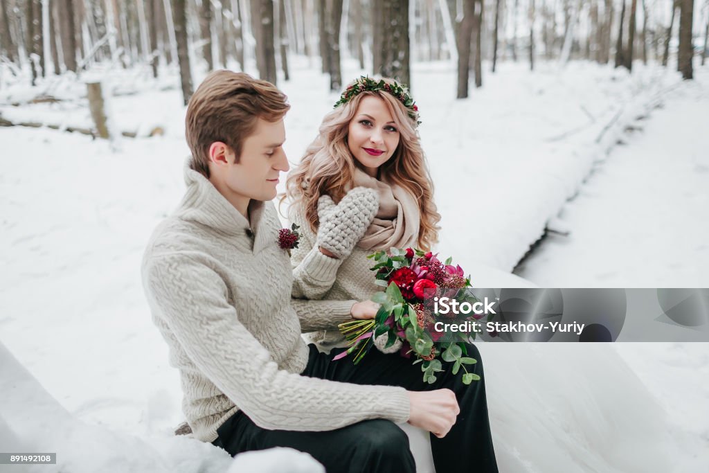 Beautiful bride and groom posing on background of snowy forest. Selective focus on the bride Beautiful bride and groom posing on background of snowy forest. Selective focus on the bride. Copy space Adult Stock Photo