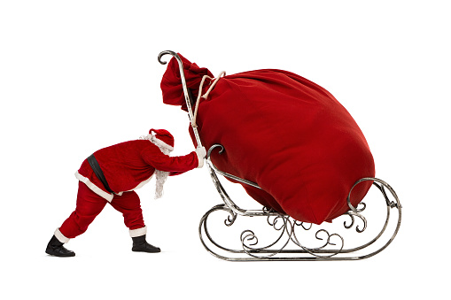 Close up of Santa Claus pushing sleigh with huge bag of christmas gifts on it, isoolated on white background