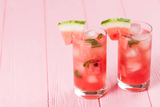 limonata di anguria con ghiaccio e foglie di menta. limonata fatta in casa di bacche mature con maturazioni rosse e verdi. bicchiere di tè freddo all'anguria. bevanda estiva rinfrescante. cocktail su sfondo ligneo - watermelon foto e immagini stock