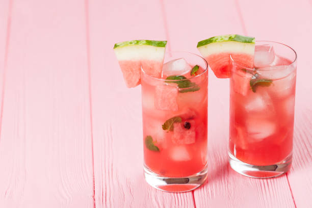 Watermelon lemonade with ice and mint leaves. Homemade lemonade of ripe berry with red and green ripes. Glass of cold watermelon tea. Refreshing summer drink. Cocktail on a wooden background Watermelon lemonade with ice and mint leaves. Homemade lemonade of ripe berry with red and green ripes. Glass of cold watermelon tea. Refreshing summer drink. Cocktail on a wooden background. punch drink stock pictures, royalty-free photos & images