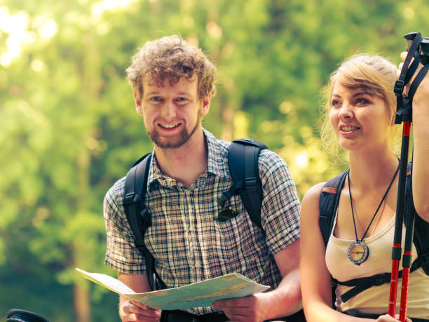 istock Hikers backpackers couple reading map on trip. 891537196