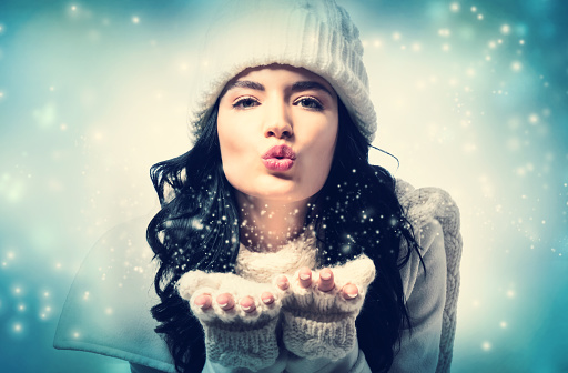 Happy young woman with winter clothes blowing a kiss