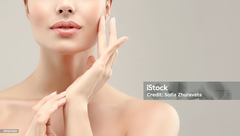 Gorgeous, young woman with clean, fresh skin is touching own face. Cosmetology. Gorgeous, young, brown haired woman with clean fresh skin is touching the face.  Symbolic image of facial treatment, cosmetology, beauty technologies and spa. Close-up detail. Beauty Stock Photo