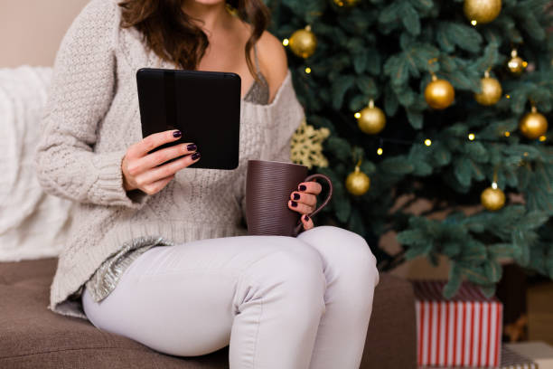 istock Woman reading e-book near the Christmas tree 891541572