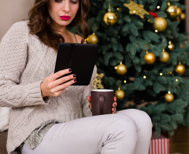 istock Woman reading e-book near the Christmas tree 891543826