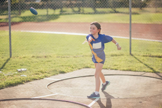 petite fille faisant discus jetant en athlétisme club - lancer du disque photos et images de collection