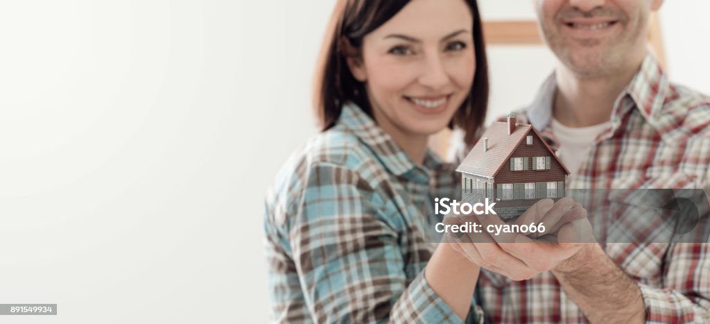 Dream house Happy couple holding their dream house in their hands, real estate and home insurance concept Home Ownership Stock Photo