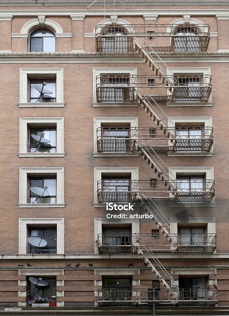 brick building with fire escape stairs and satellite dishes  Apartment Stock Photo