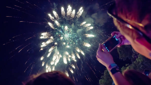 istock Woman photographing fireworks celebration 891557106