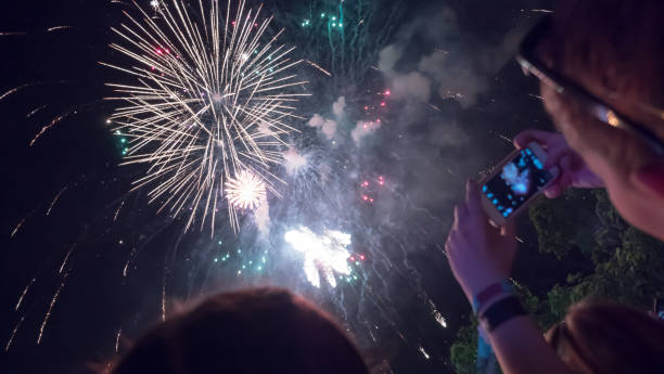 istock Woman photographing fireworks celebration 891557852