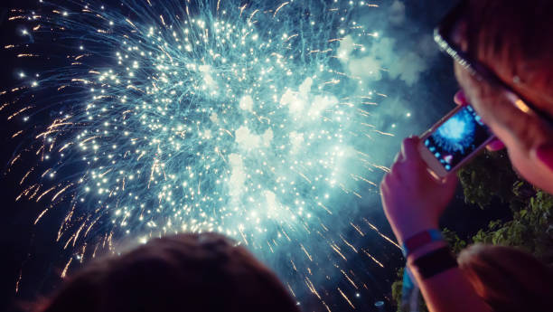 istock Woman photographing fireworks celebration 891559360